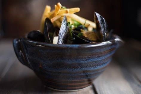 Fresh black mussels in a blue ceramic bowl