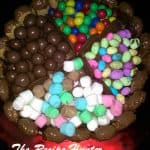 A birthday cake with butter cream, topped with chocolates and various other candy