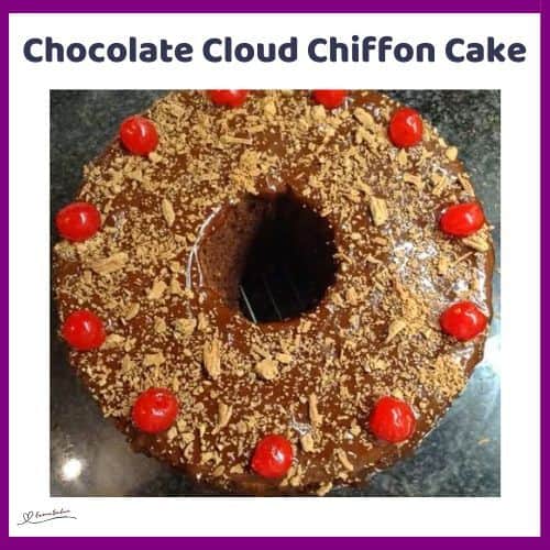 an image of a Chocolate Cloud Chiffon Cake decorated with flake chocolate and cherries