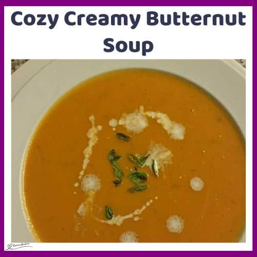 an image of a Cozy Creamy Butternut Soup in a white soup bowl with a drizzle or cream and greens