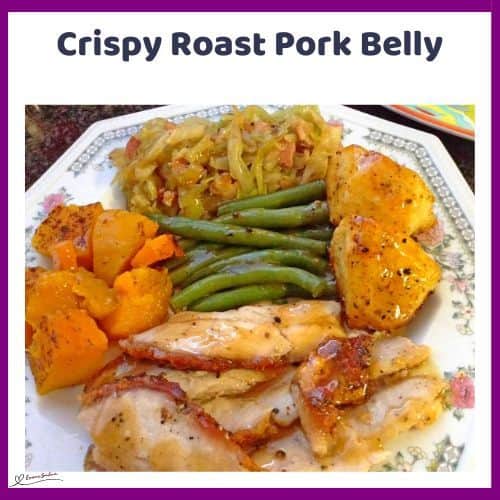 an image of a dinner plate with Crispy Roast Pork Belly, bacon cabbage, green beans and potatoes