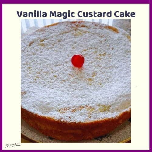 An image of a Vanilla Magic Custard Cake dusted with caster sugar and decorated with a single red cherry