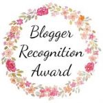 Logo of Blogger Recognition Award a circle of light pinkish flowers with overlay Blogger Recognition Award