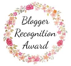 Logo of Blogger Recognition Award a circle of light pinkish flowers with overlay Blogger Recognition Award