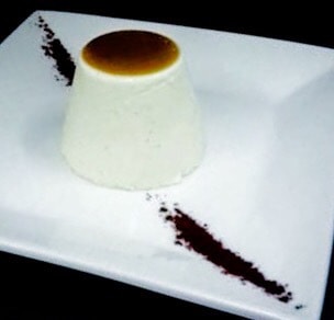 Caramel Panna Cotta with Frangelico Liquor a dessert on a white plate with vanilla pod in the corner
