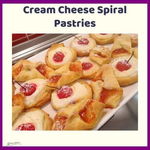 An image of a batch of Cream Cheese Spiral Pastries dotted with cherries or jam