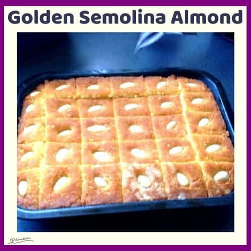 An image of a Golden Semolina Almond Cake in a baking pan, cut into squares with an almond on each