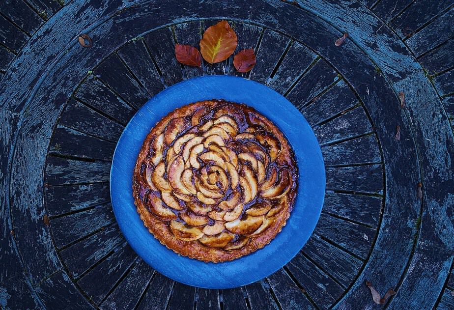 Apple and Caramel Tart in blue plate on dark wooden background