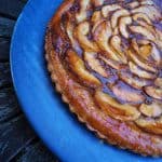 Apple and Caramel Tart in a blue plate on a dark wooden table