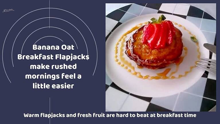 An image of a stack of Banana Oat Breakfast Flapjacks with a sliced strawberry and syrup