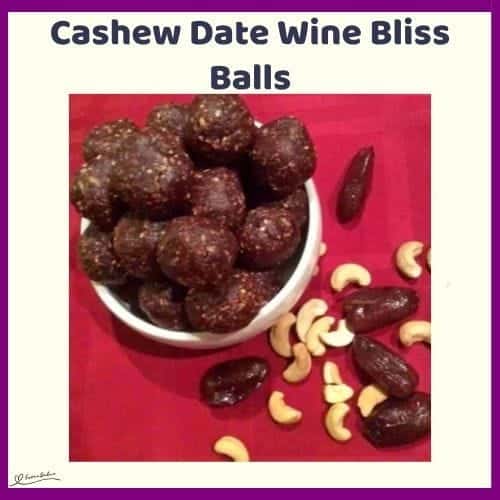 An image of a white bowl with Cashew Date Wine Bliss Balls on a red background