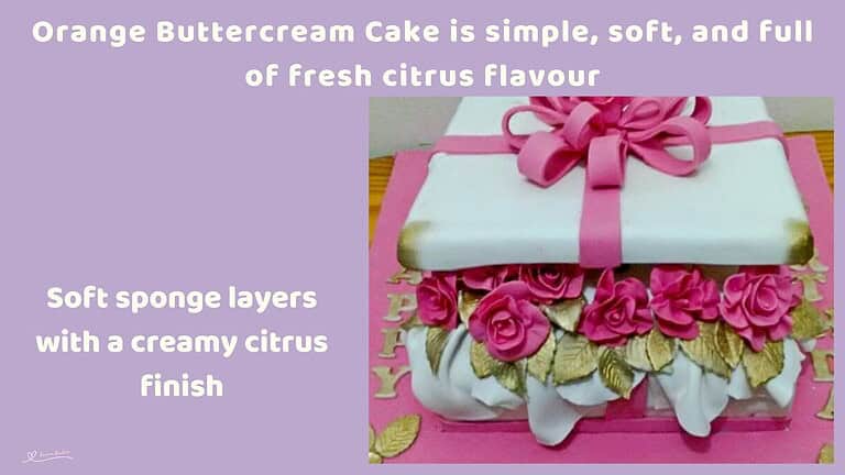 An image of an orange buttercream cake in the shape of a gift with a pink bow and pink roses between the layers
