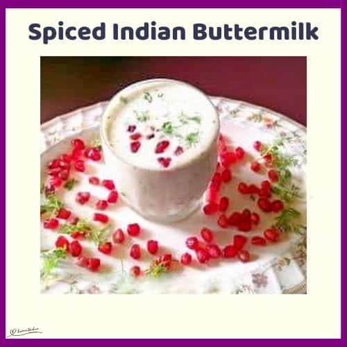An image of a glass with Spiced Indian Buttermilk and garnishes with fresh coriander leaves, pomegranate seeds