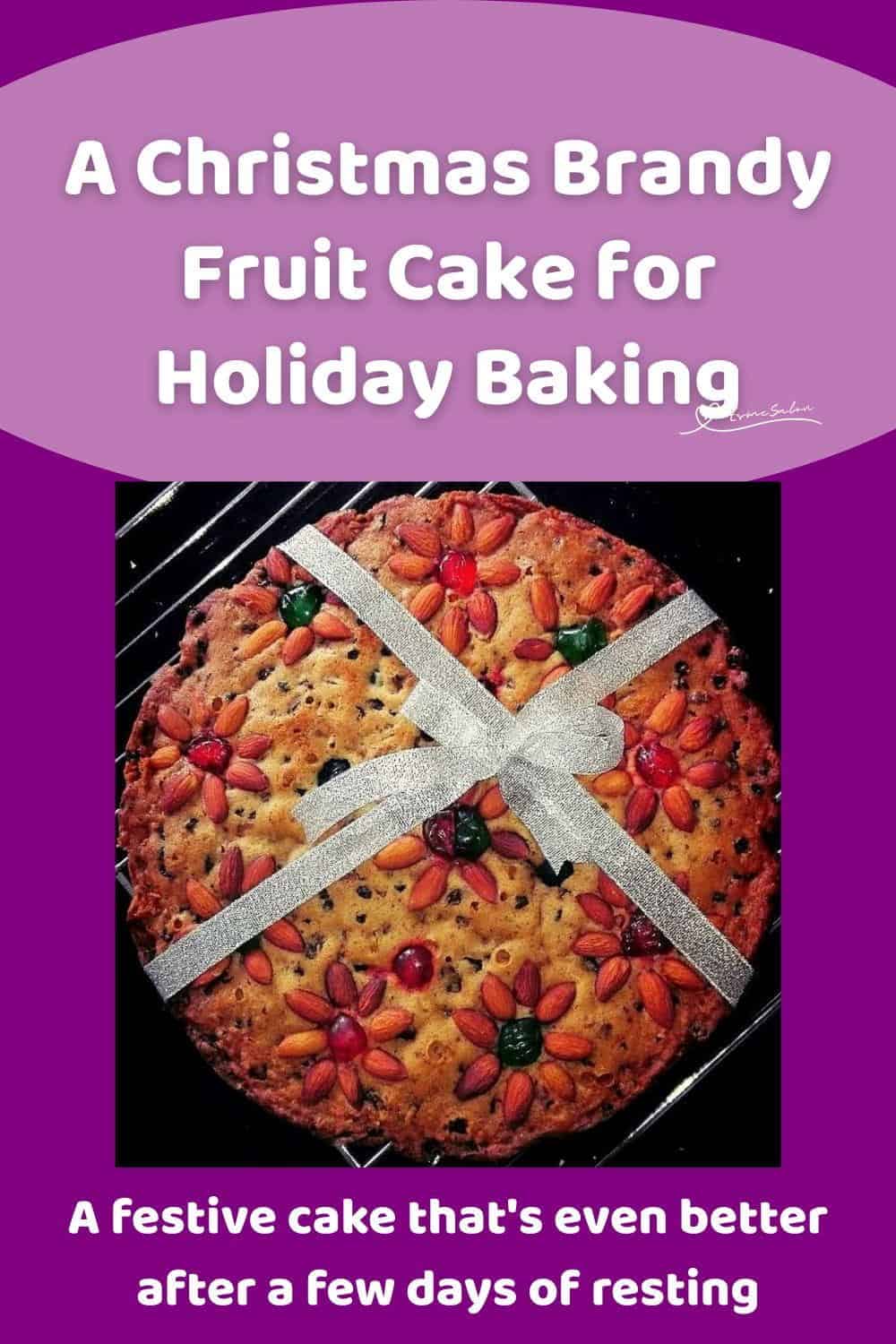 An image of a Christmas Brandy Fruit Cake Decorated with Nuts, Cherries and a Ribbon