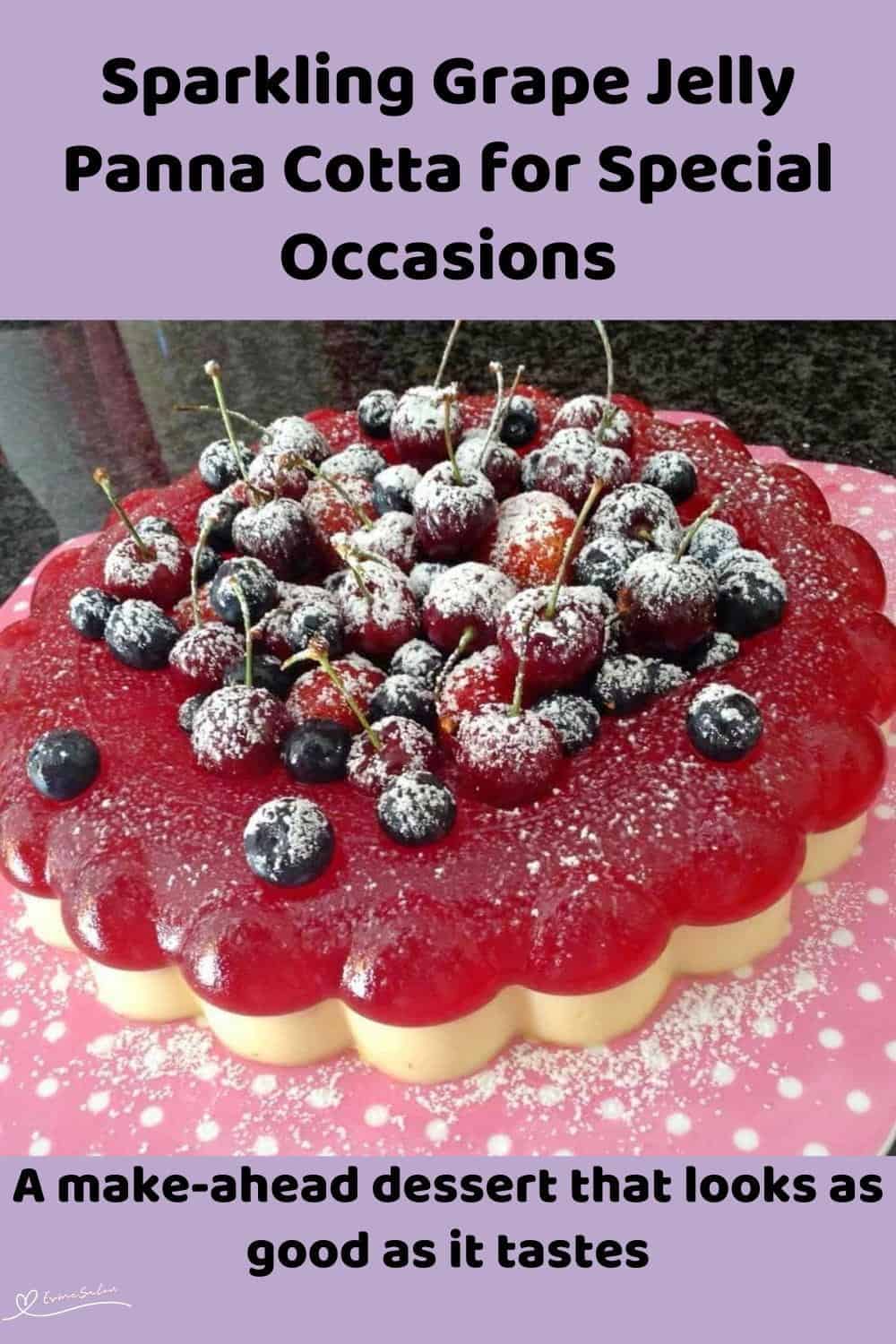 An image of a Sparkling Grape Jelly Panna Cotta, decorated with frosted cherries and fresh berries and a dusting of icing sugar