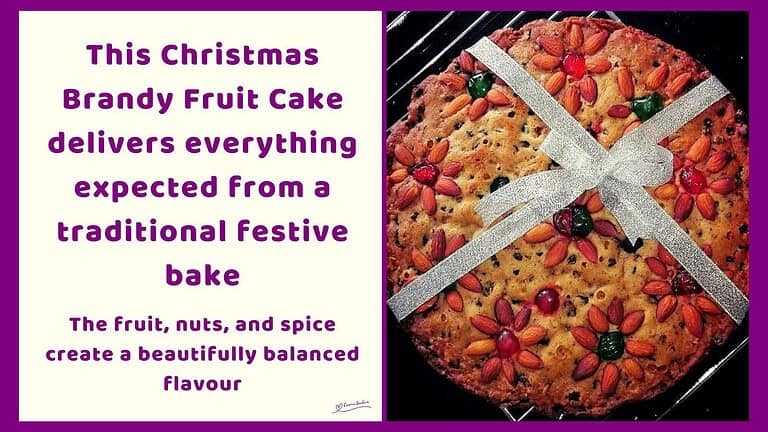 An image of a Christmas Brandy Fruit Cake Decorated with Nuts, Cherries and a Ribbon