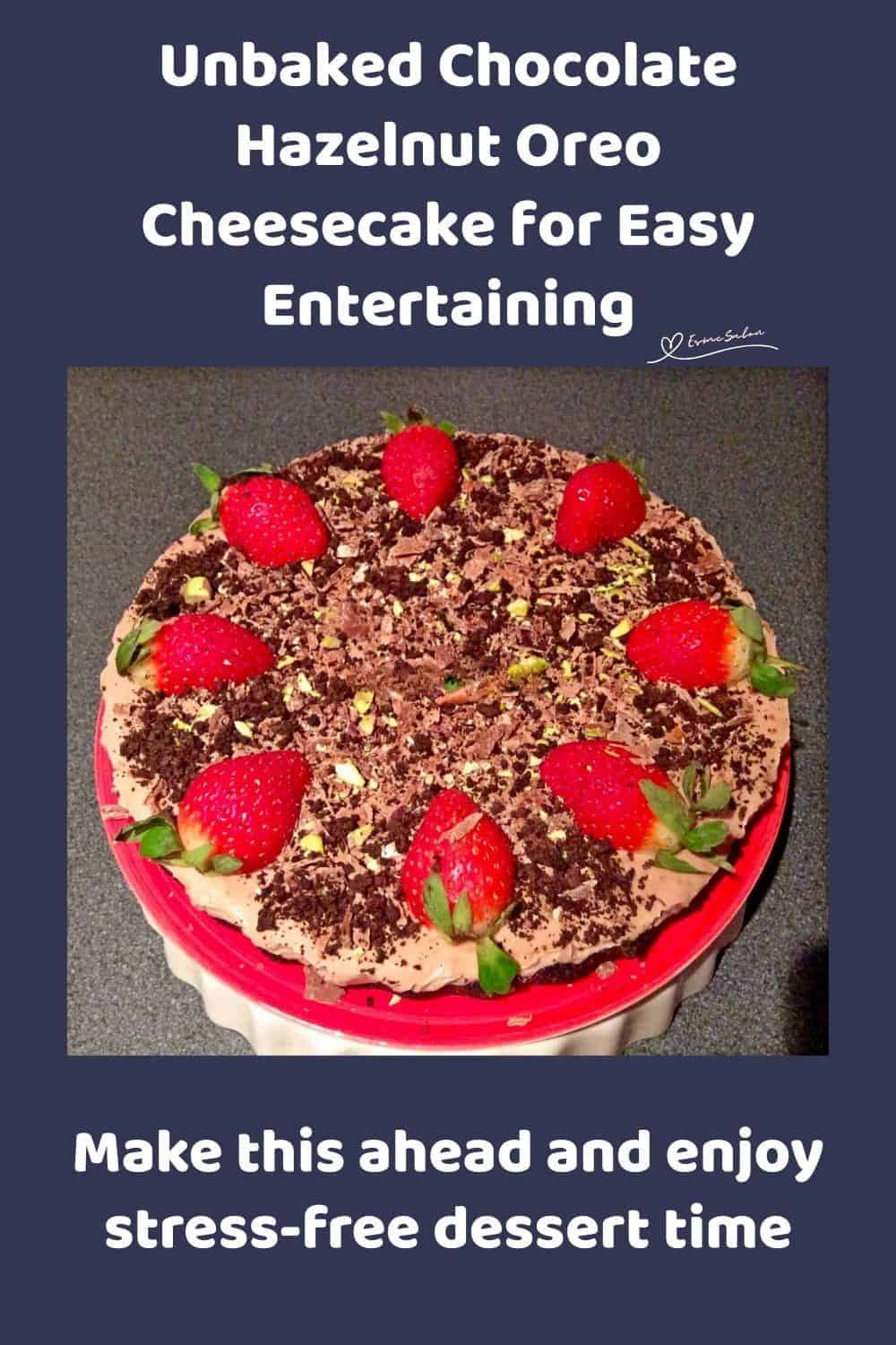 An image of a round Unbaked Chocolate Hazelnut Oreo Cheesecake decorated with strawberries, pistachios, Toblerone shavings, and the crushed Oreo biscuits
