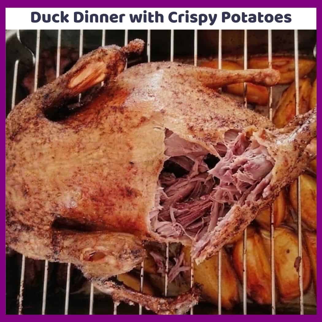 An image of a Duck roasting with potatoes underneath the rack