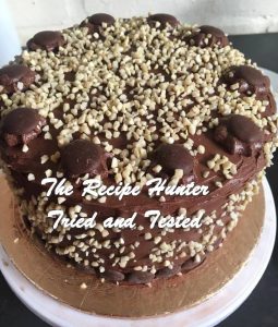 Round Chocolate Delight Cake with buttercream frosting and decorated with chocolate buttons and nuts