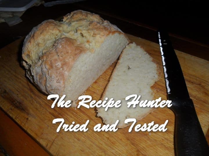 a round Buttermilk Bread sliced and on a cutting board with a bread knife on the side