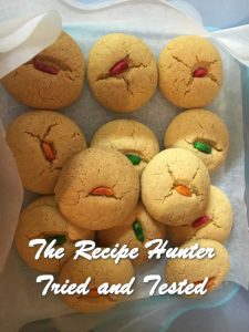 Nankhatai Biscuits packed in a plastic container and each decorated with a colored almond