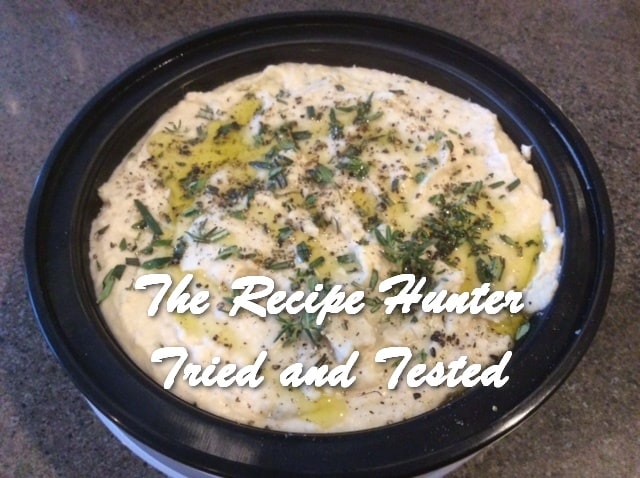 an image of a black bowl with White Bean and Herbs Hummus, dressed with oil