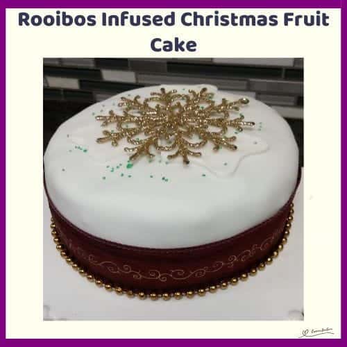 An image of a Rooibos Infused Christmas Fruit Cake covered with white marzipan and decorated with Christmas balls and starts