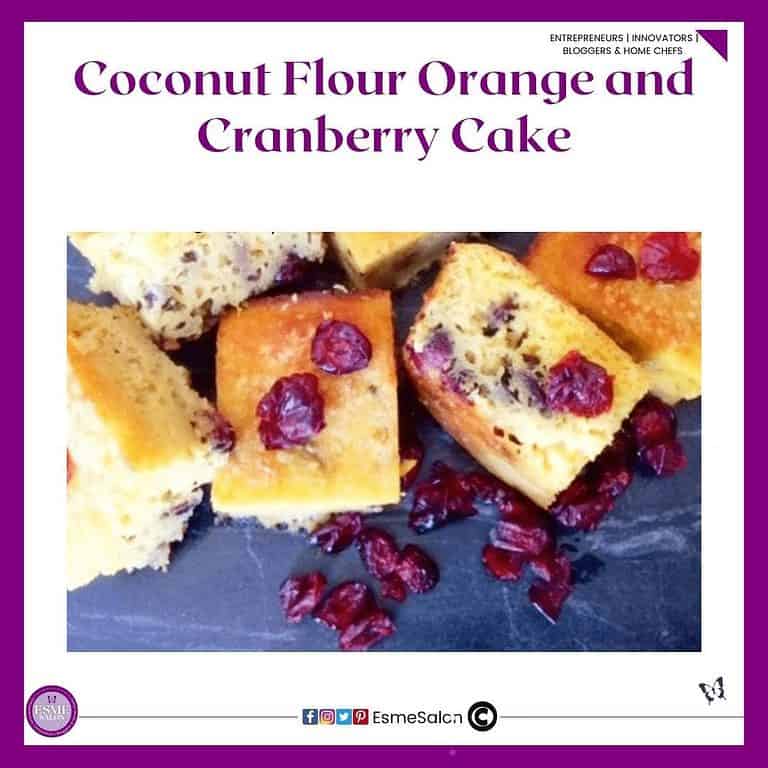 an image of a batch of Coconut Flour Orange and Cranberry Cake cut into blocks with some dried cranberries on and in front of them