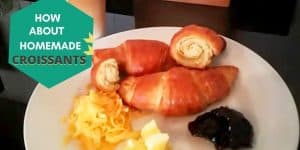 croissants with butter, jam and cheese on a white plate