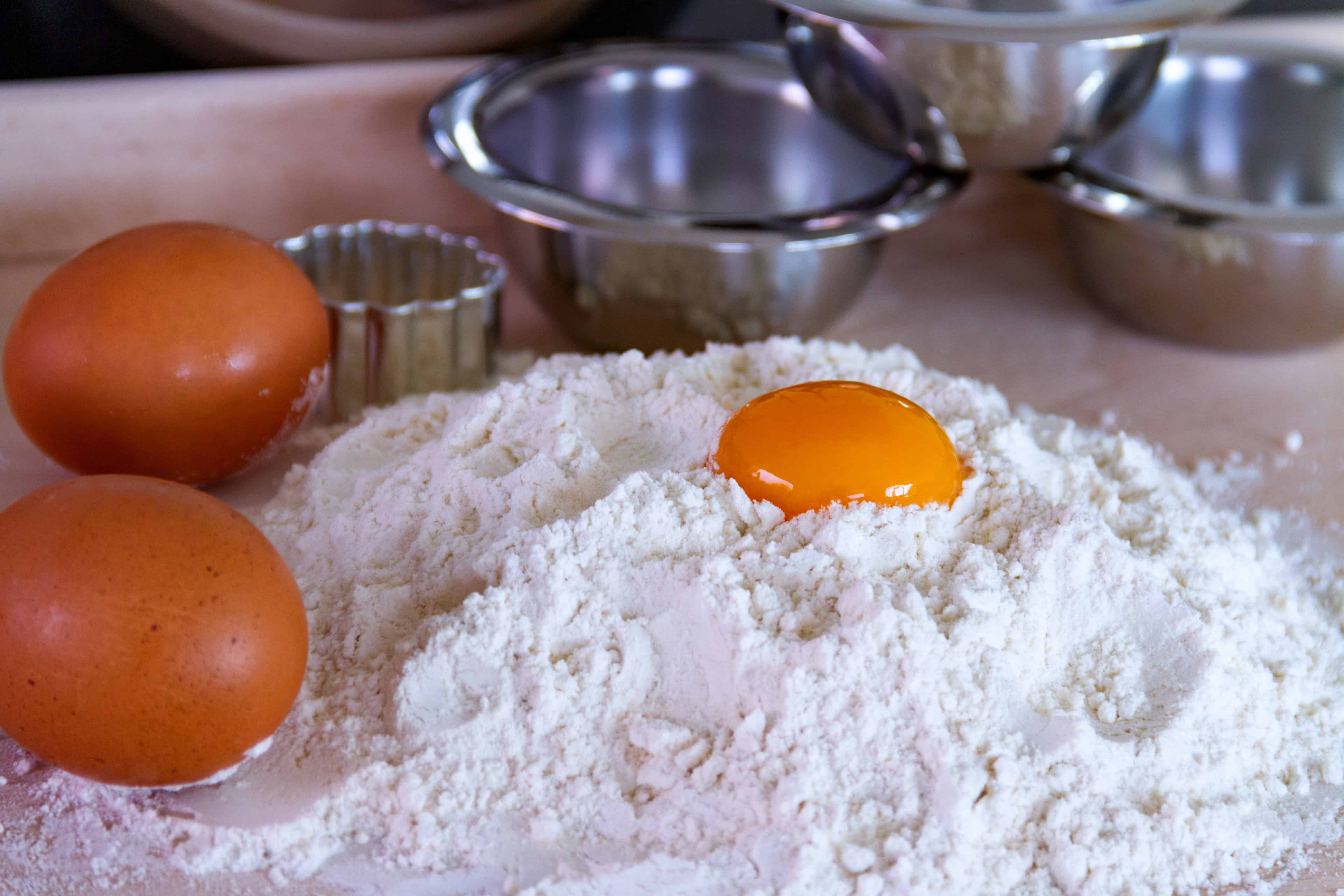 Flour eggs and butter next to a stainless mixing bowl