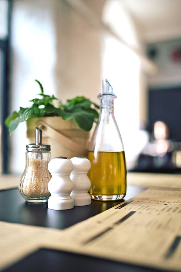 Bottle of Oil on counter next to white salt and pepper pot