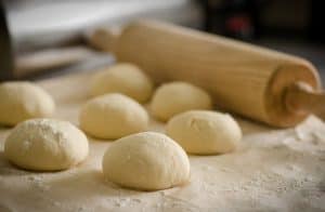 Fresh dough with wooden rolling pin