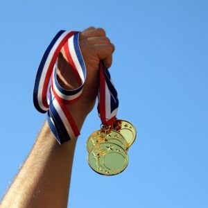 Hand holding 3 Gold Medals in the air