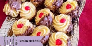 Melting moment cookies dipped in chocolate on the one side with a red cherry in the center