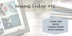 glass vase with pink, lilac and yellow flowers with a collection of magazines and computer screen and keyboard