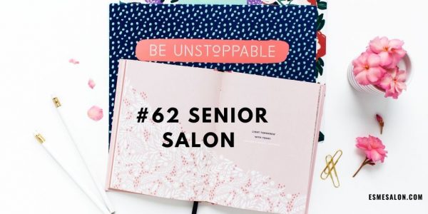 floral pink notepad, with white pencils, golden paperclips and pink flowers on a blue dotted cloth