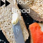 Keto Almond Flour Bread with sesame seed, sliced bread buttered and lox added on a black board with