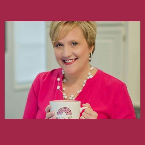 Picture of Tracie Forbes wearing a pink top and holding a white and pink coffee mug in her hands. She's from Blogger Education Network