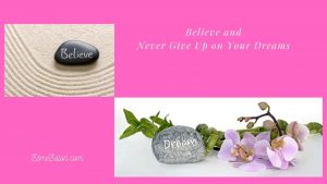 sand with a black stone and believe written in white and some lilac Orchids with a grey stone and dream written in white on it