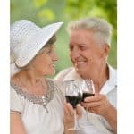 Lady with white hat and man sharing a glass of red wine