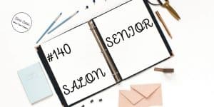 white binder with brown envelopes, blue notebook, blue paintbrushes, pen and scissor