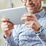 Gentleman with blue striped shirt smiling with iPad in hand