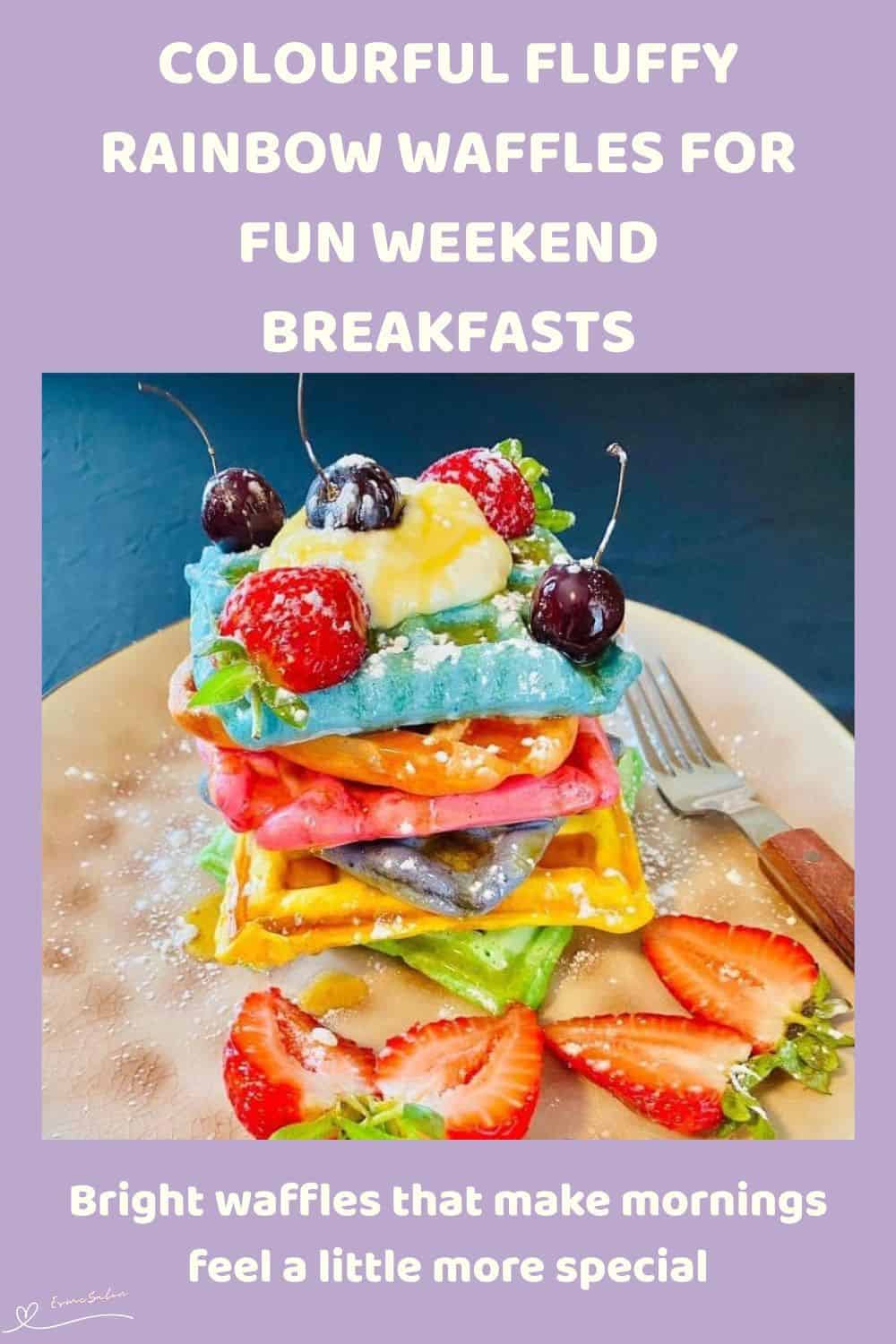 An image of a stack of colourful, fluffy, rainbow waffles with fruit and some cherries
