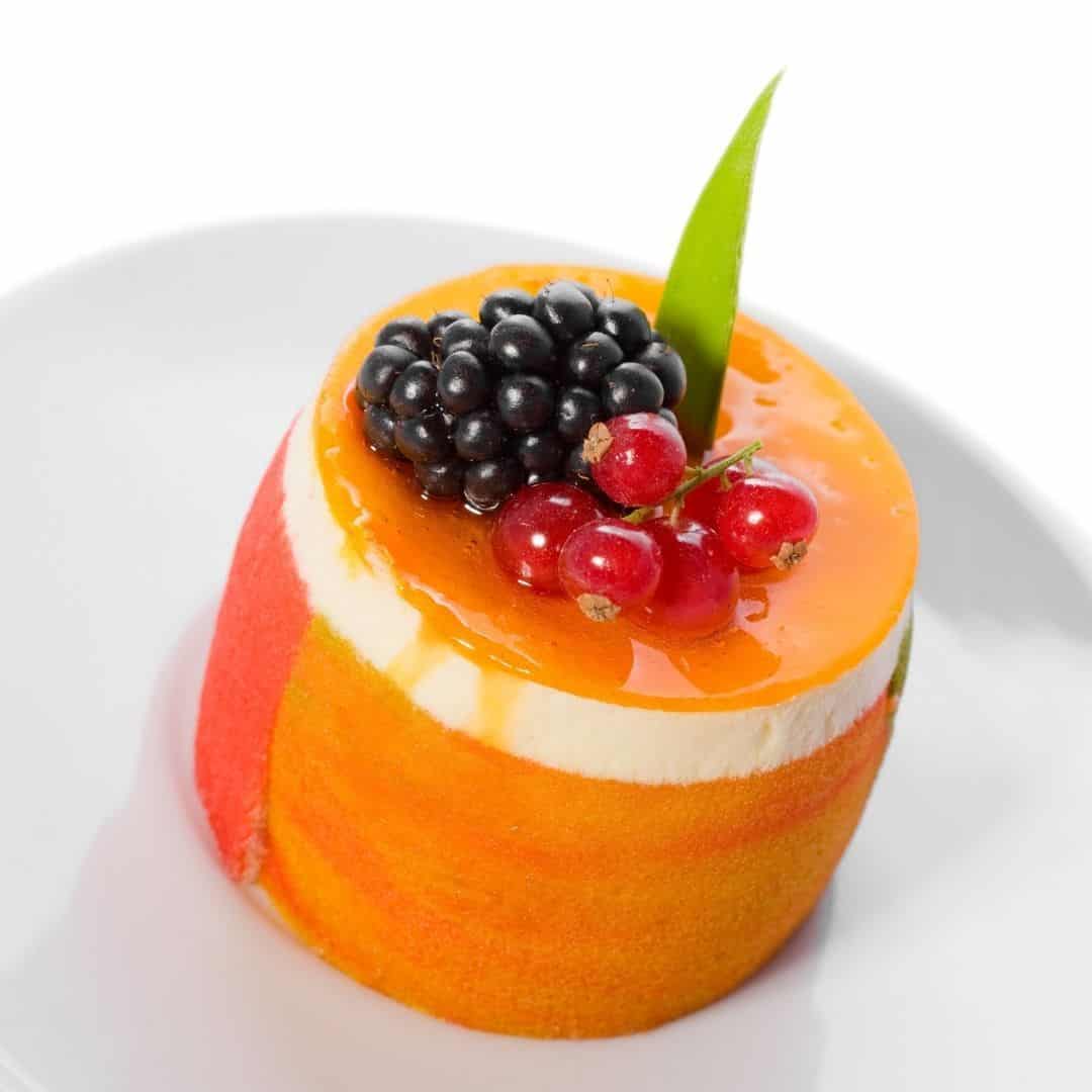 An image of a single round dessert with fruit and cherries as decoration