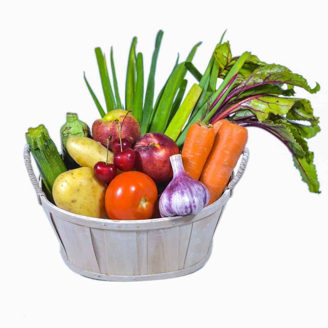 A white washed wooden basket with Fruits, Vegetables, and Other Produce