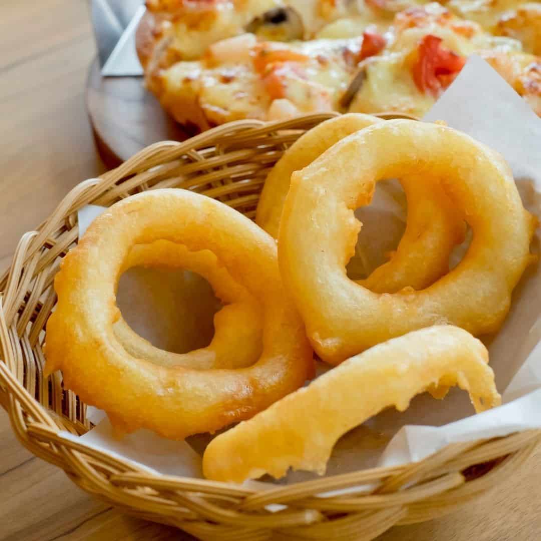 An image of a wicker basket with friend onion rings