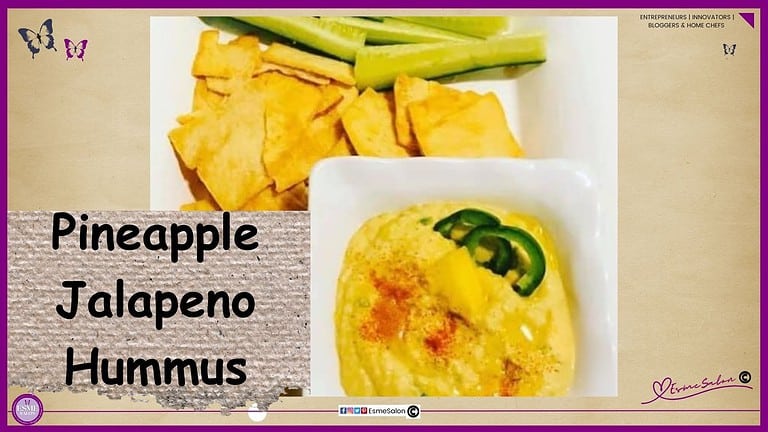 an image of a white plate with cucumber sticks, carrots and crackers as well as a bowl of Pineapple Jalapeno Hummus drizzles with oil and decorated with peppers