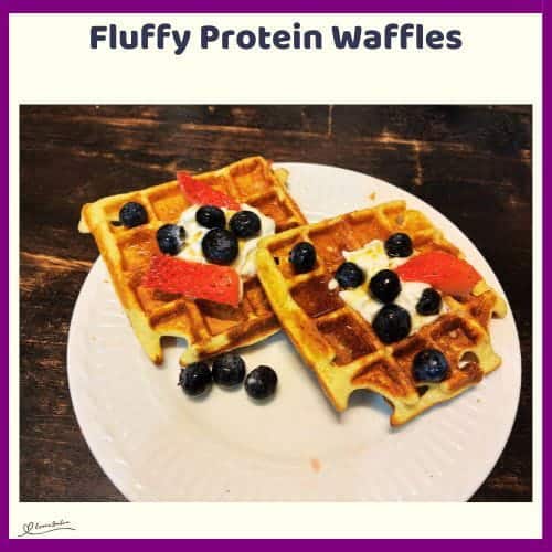 An image of Fluffy Protein Waffles with a dollop of cream, blue berries and strawberries