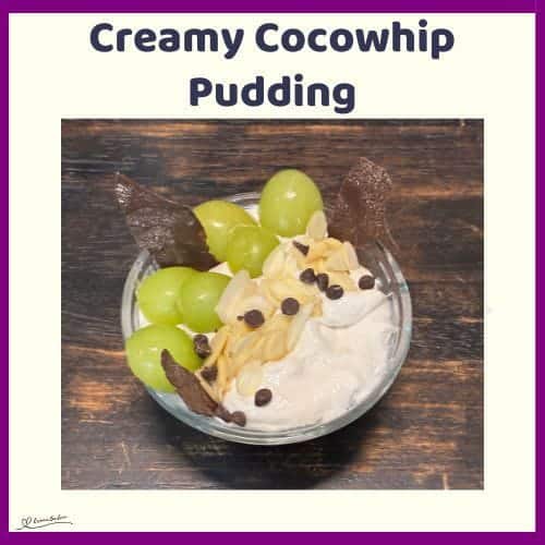 An image of a Creamy Cocowhip Pudding in a small bowl with grapes, slivered almonds and chocolate chips